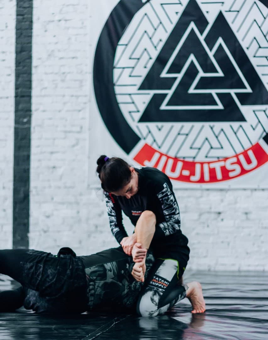 Парна робота на фоні логотипа Avangard Jiu-Jitsu